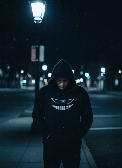 Model in a black Sovereign Grin hoodie standing under a streetlamp on a dark city street at night.