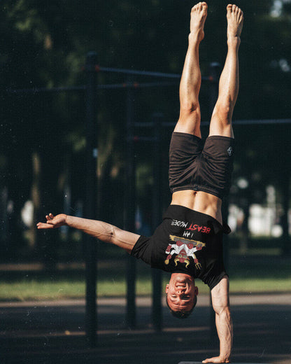 Athlete performing a one-handed handstand at an outdoor gym, wearing the Sovereign Emblem "Beast Mode" t-shirt.