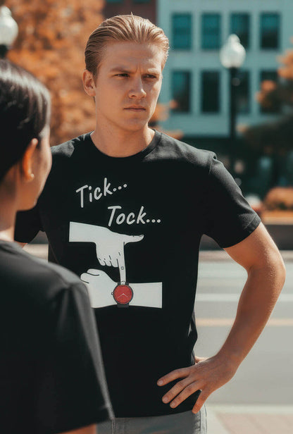 Model with an impatient expression on a city street, wearing the Sovereign Emblem "Tick... Tock..." t-shirt.